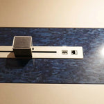 Load image into Gallery viewer, Silver metallic cable management strip with hdmi ethernet ports and black textured device on grey office meeting table back side