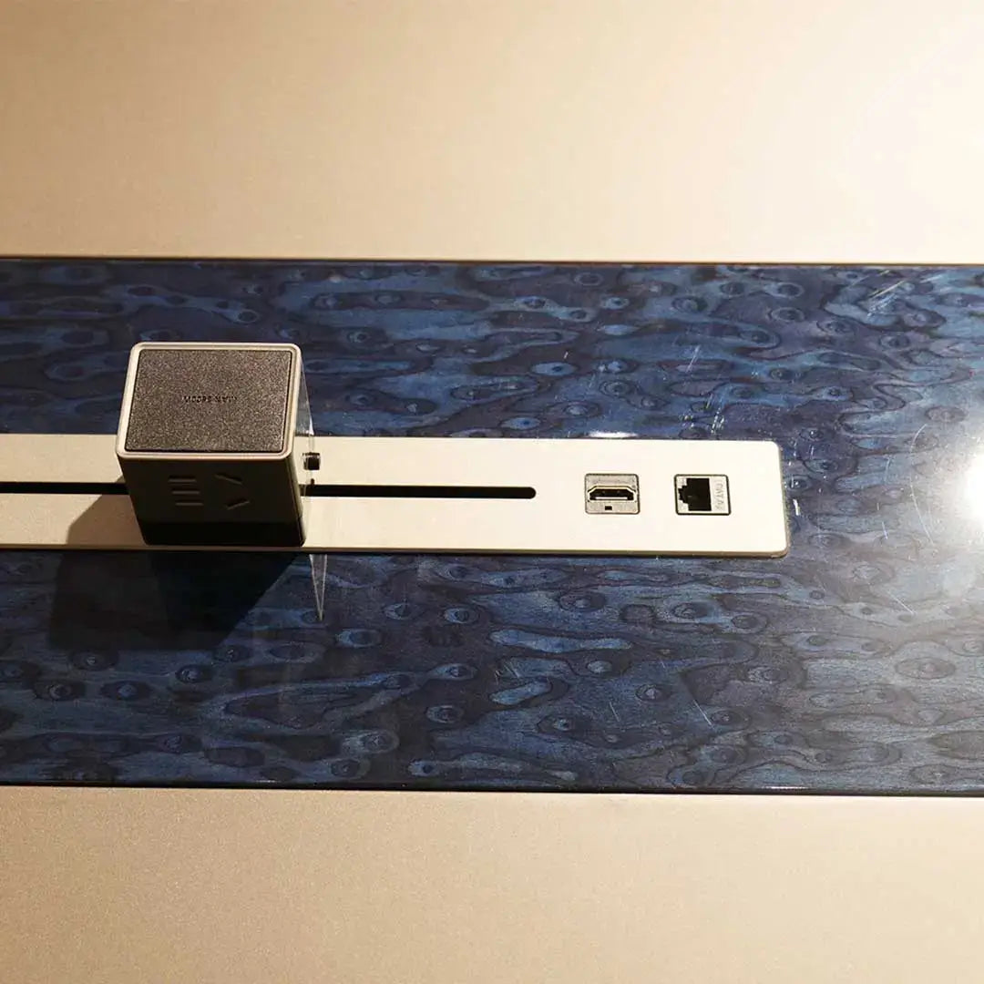 Silver metallic cable management strip with hdmi ethernet ports and black textured device on grey office meeting table back side